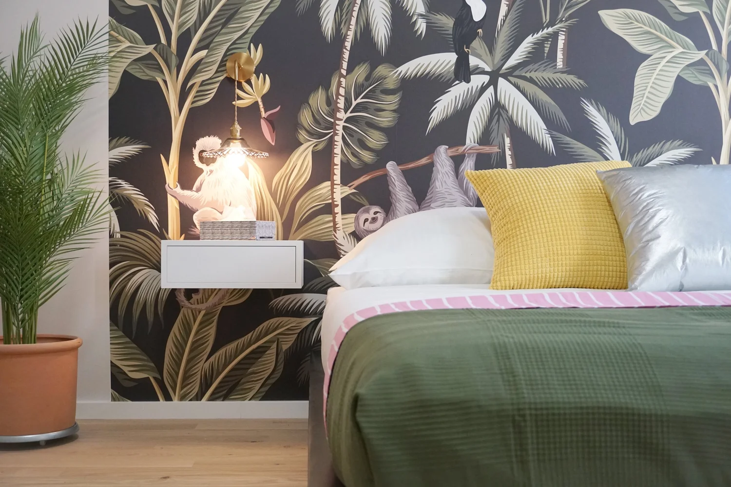 Schlafzimmer mit Dschungel-Tapete und bunten Kissen in der Toßgasse