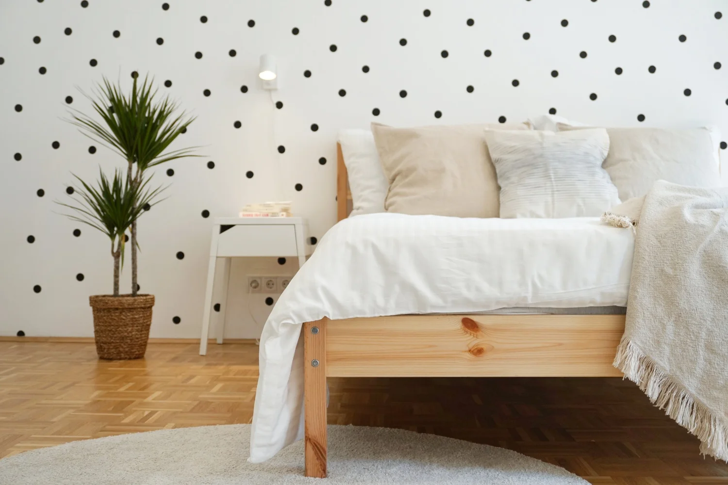 Helles Schlafzimmer mit weißem Bett und Holzparkett